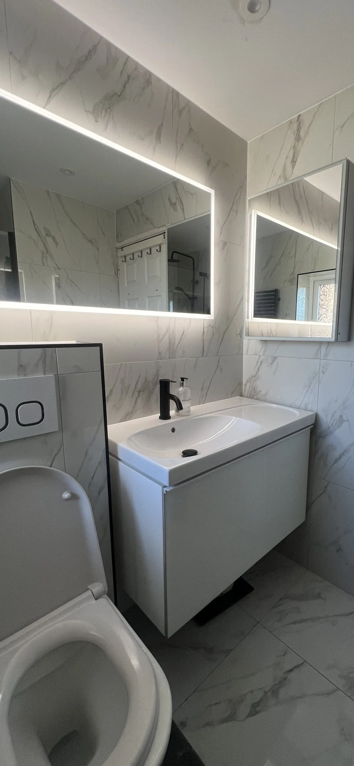 Wall-hung vanity with matt black tap, backlit mirror and mirrored cabinet
